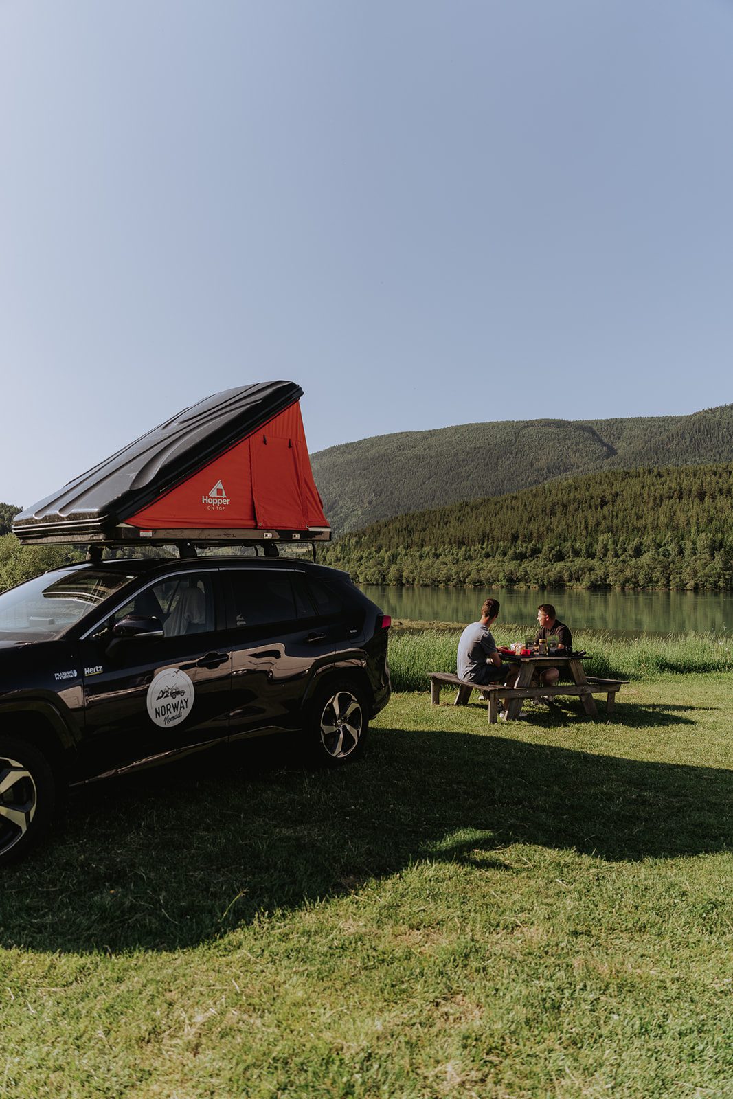 Picknick in de natuur naast een auto met daktent in Noorwegen